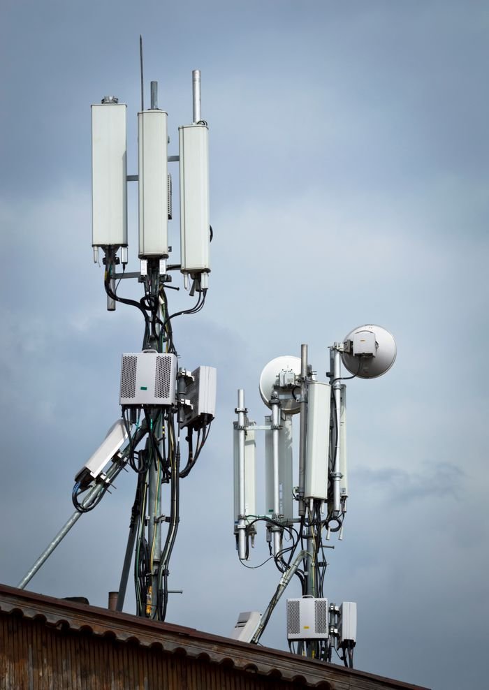 Cell tower with multiple antennas for wireless communication against an overcast sky.